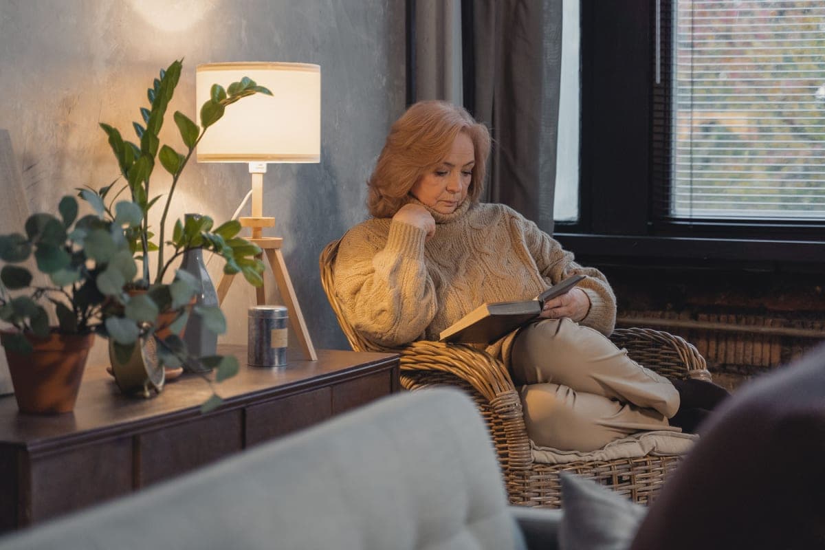 A cozy reading corner with a chair, lamp, and plants