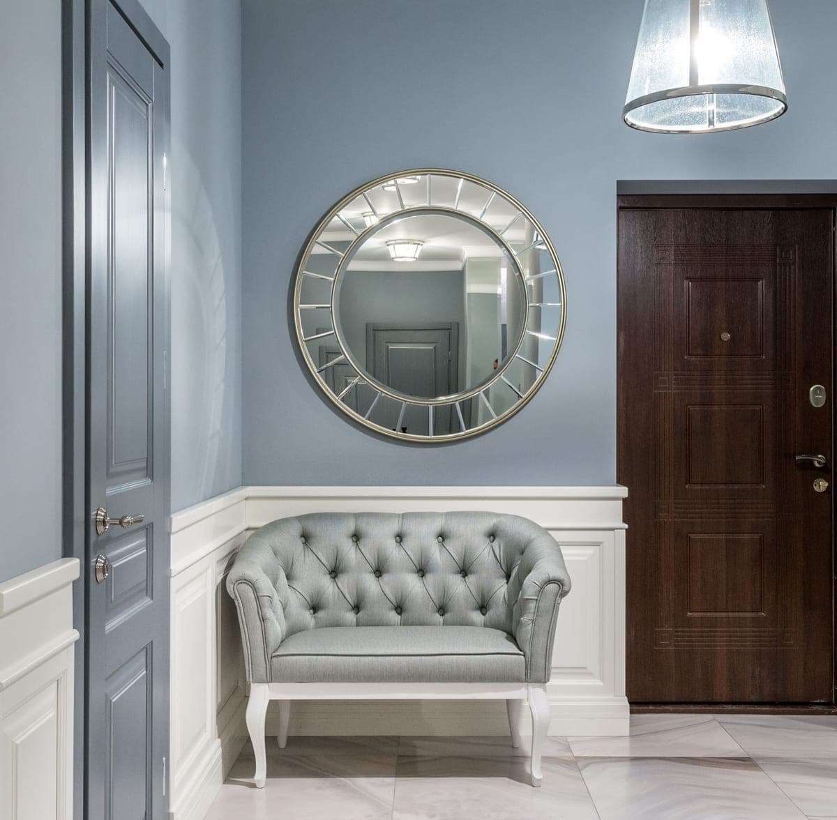 A round wall mirror in a styled entryway