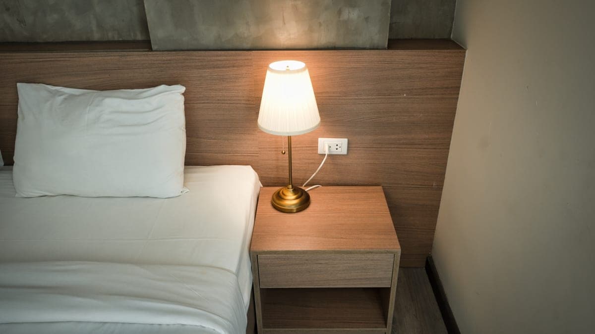 A nightstand with a bedside lamp and decor