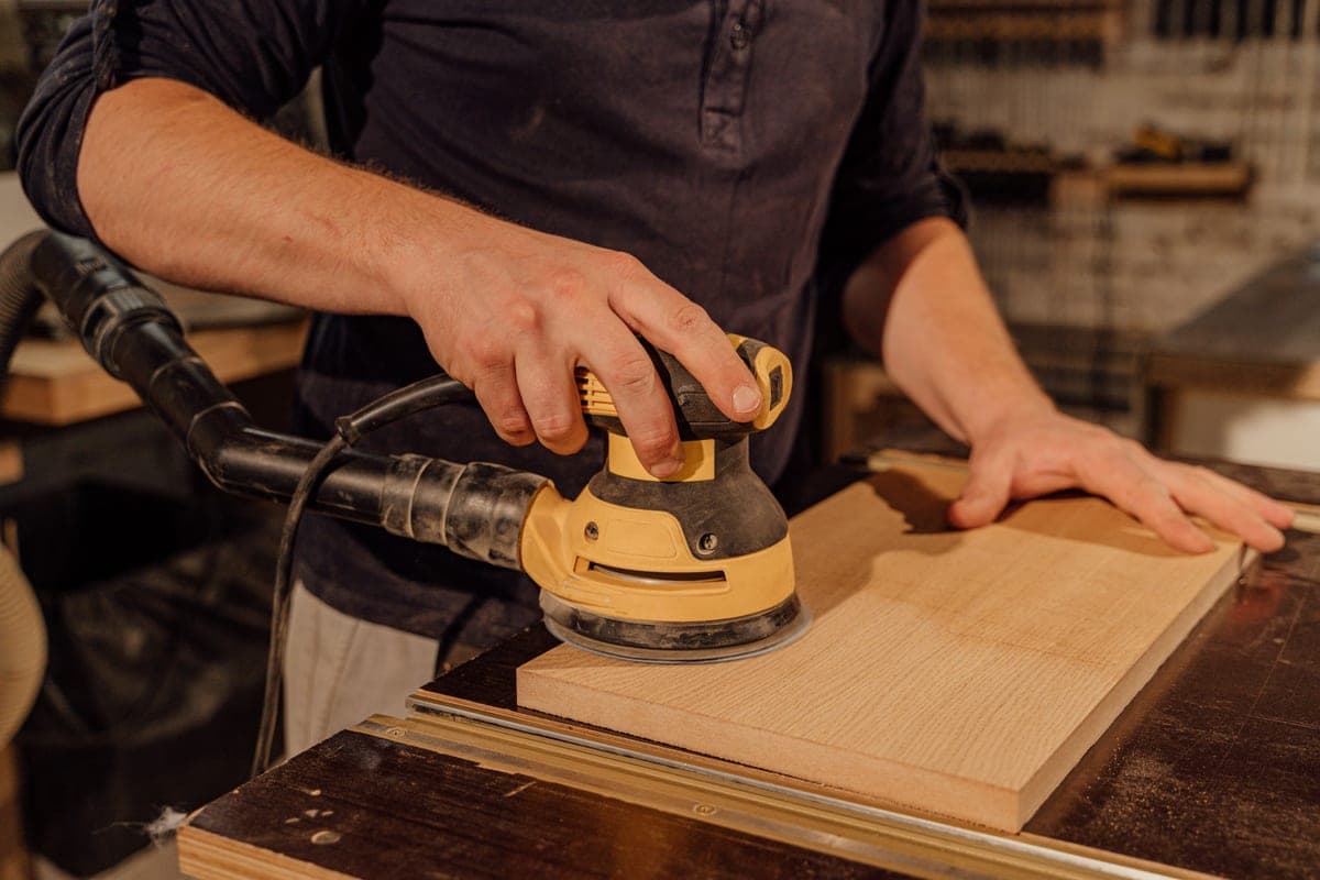 Sanding a wood surface while refinishing furniture