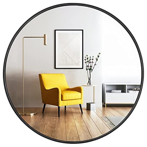 A round wall mirror in a styled entryway